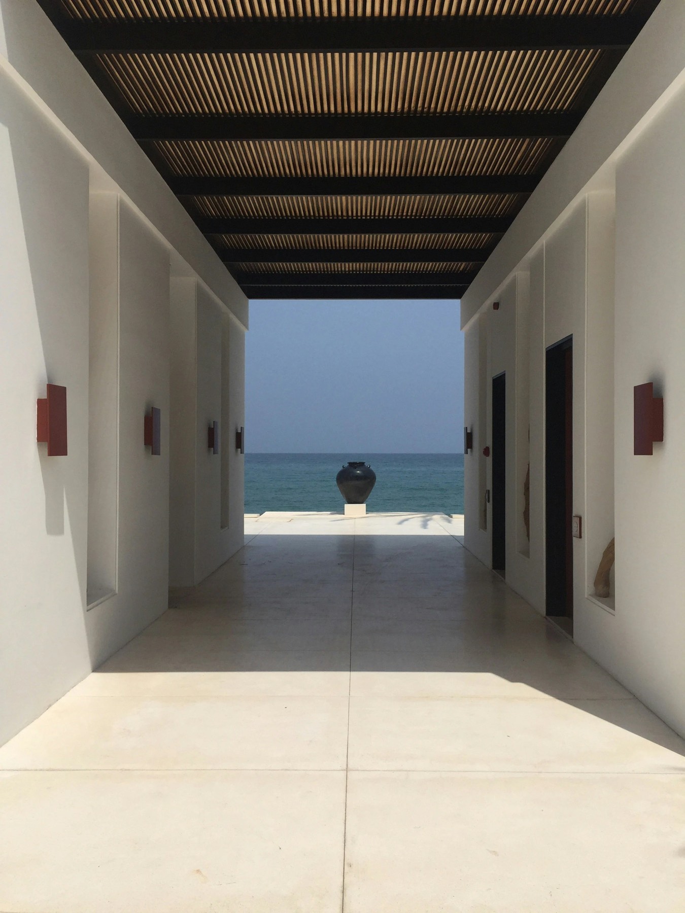 A sunlit hotel corridor opening onto the ocean